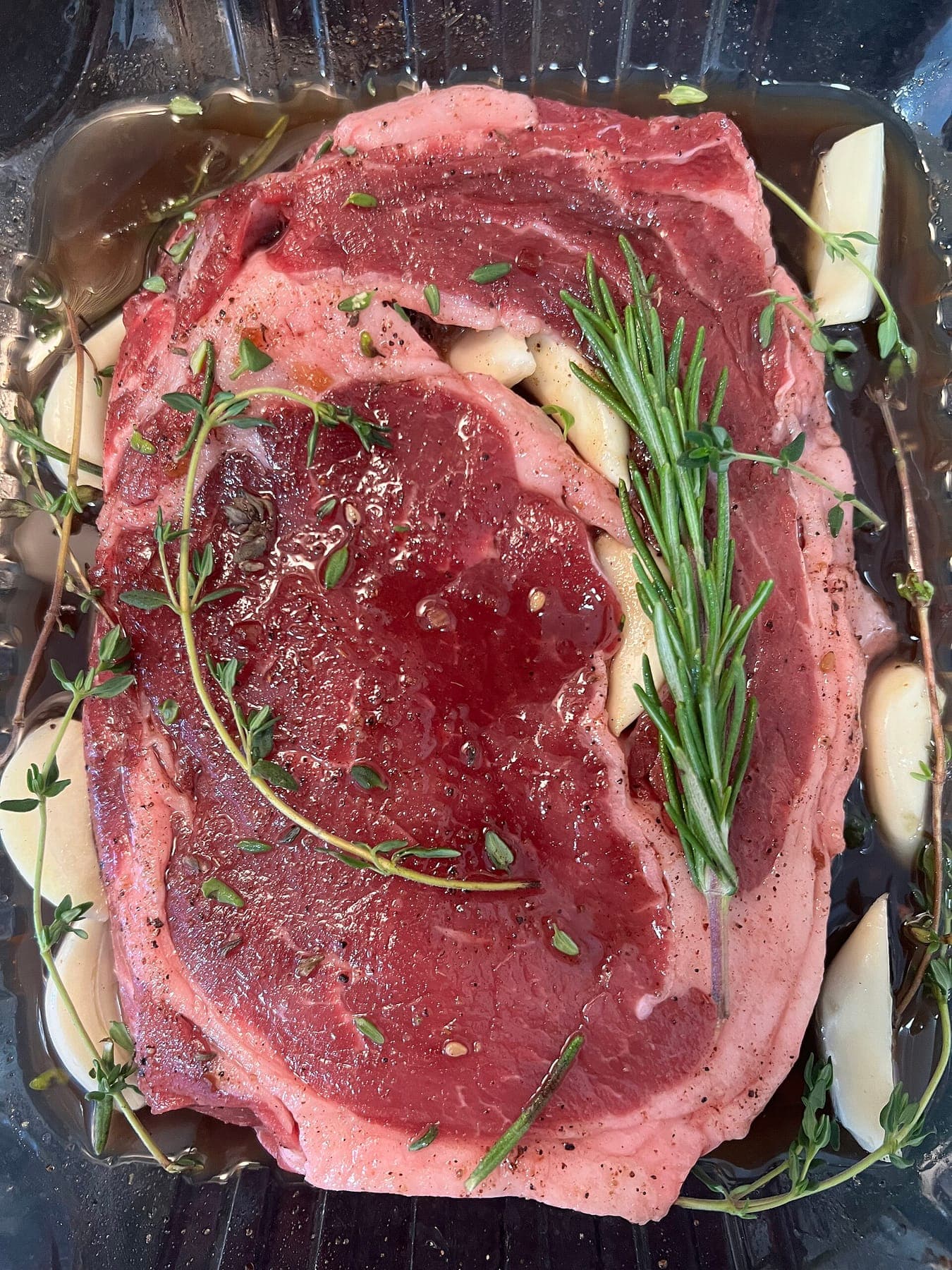 Liat Portal for Foodie Disorder - Ribeye steak preparation with garlic and fresh herbs before cooking