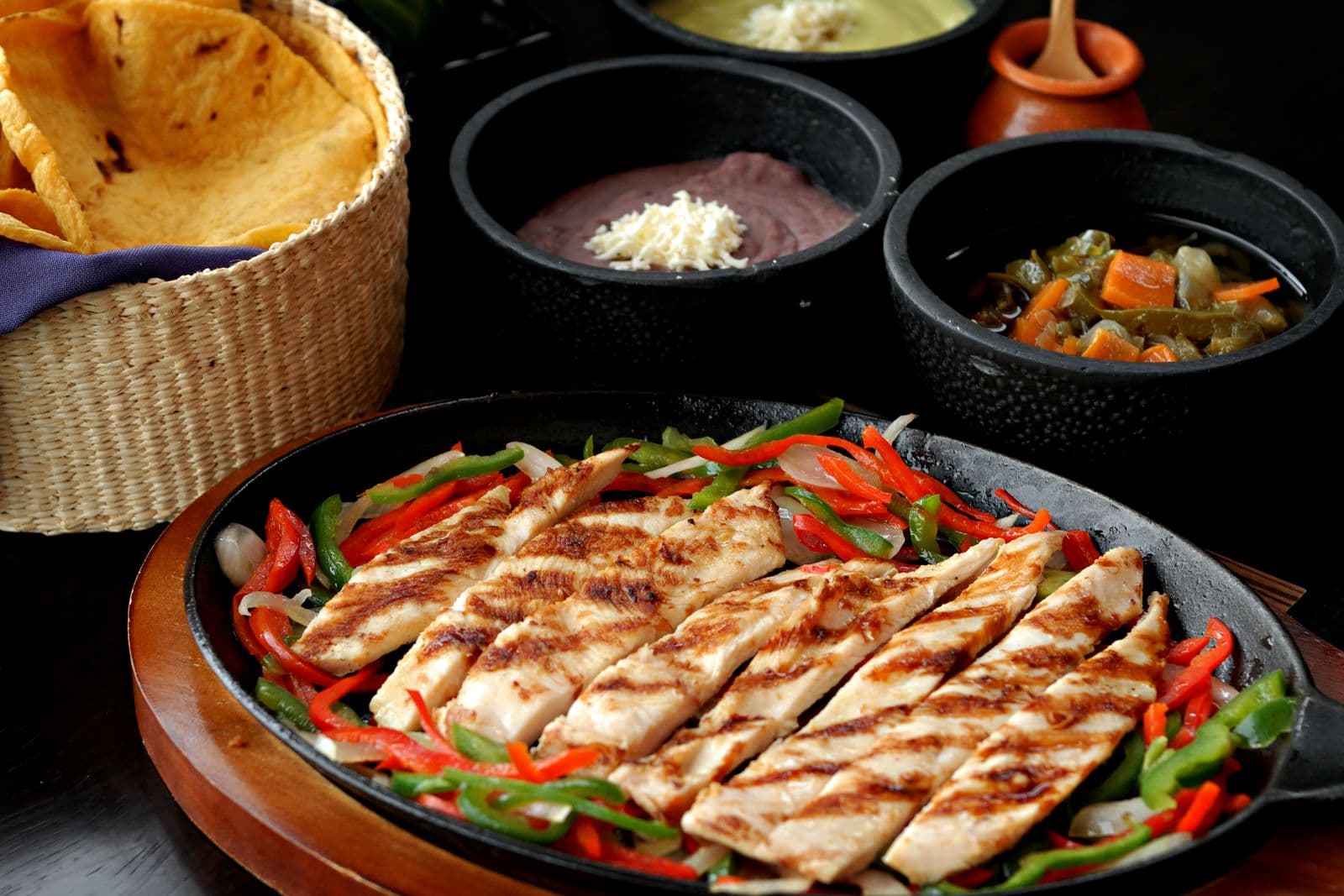 Grilled chicken fajita strips with peppers, tortillas and dips