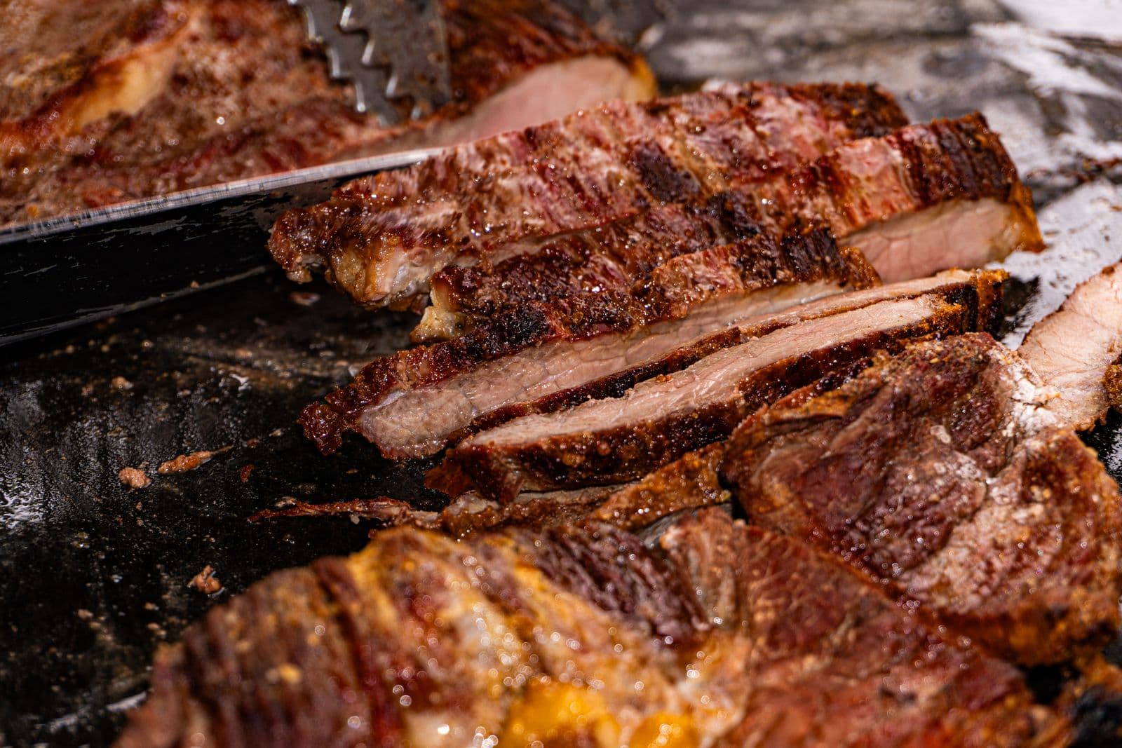 Charred carne asada sliced against the grain on the griddle