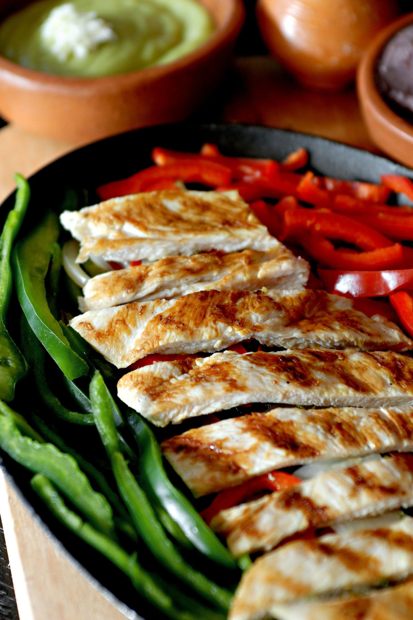 Close-up of sliced grilled chicken breast with red and green peppers
