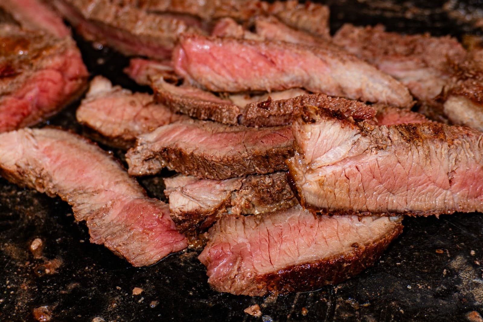 Sliced grilled steak searing on a hot griddle