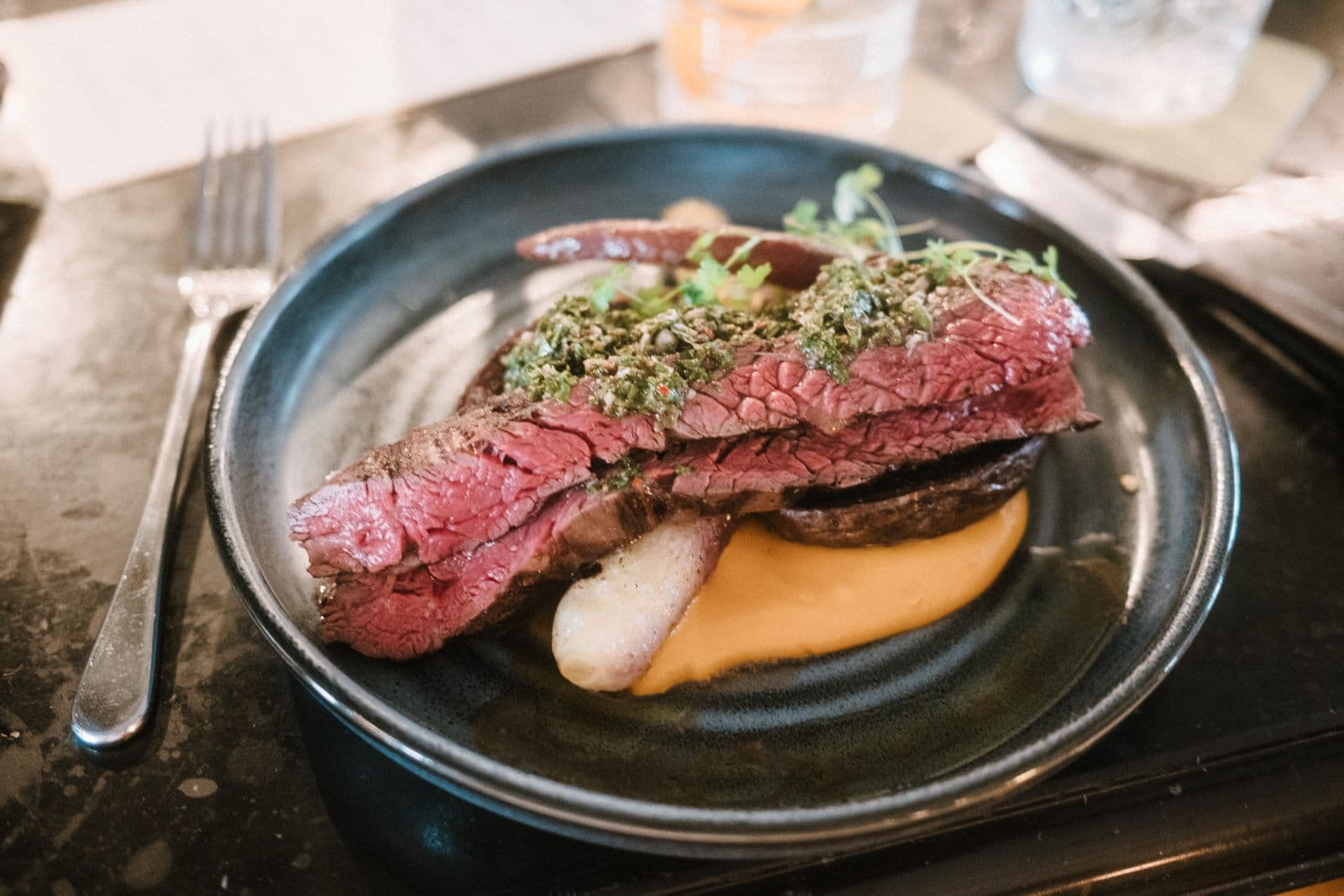 Sliced steak topped with fresh chimichurri