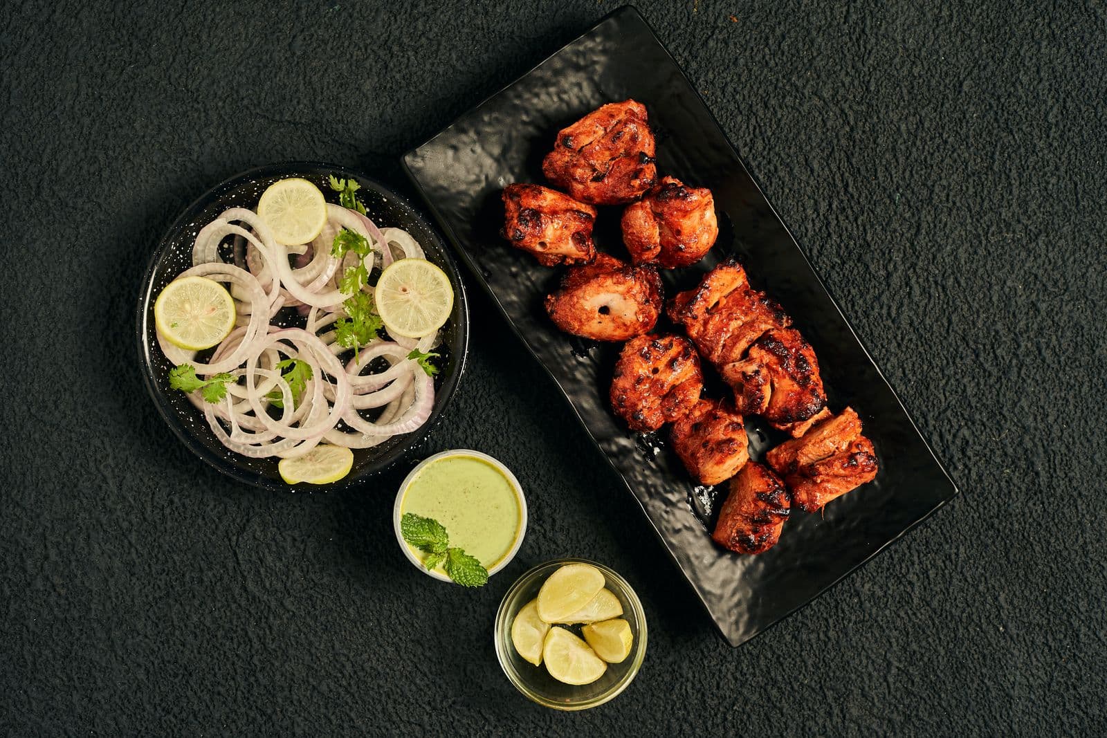 Vivid red tandoori-spiced chicken with onion salad and green chutney